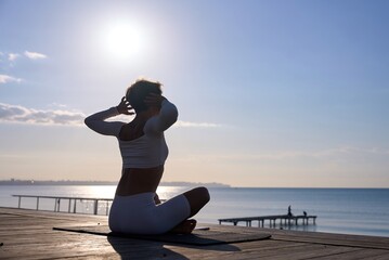 Fototapeta premium Young healthy woman practicing yoga on the beach at sunrise