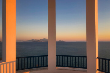 Scenic view of Mediterranean Sea and Greek islands seen through columns of a rotunda at sunset.