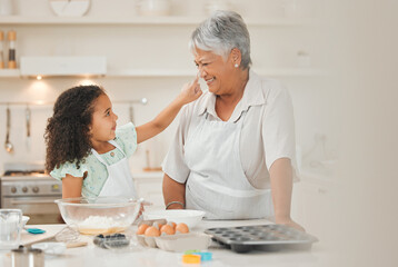 My granddaughter makes me smile. a young girl playfully putting flour on her grandmothers nose...