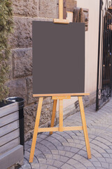 Blackboard in front of restaurant entrance. Mock up menu blank board sign stand near shop or cafe restaurant. Street magnetic sidewalk chalkboard
