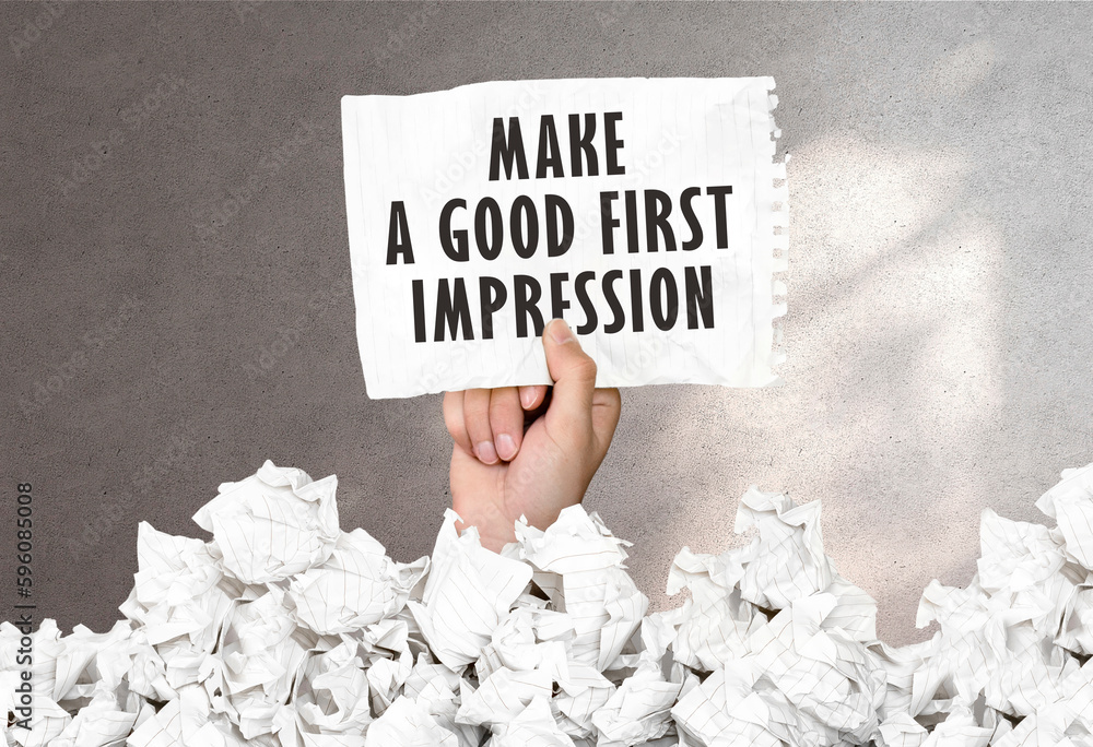 Poster hand holds a piece of paper with text make a good first impression on a gray wall background