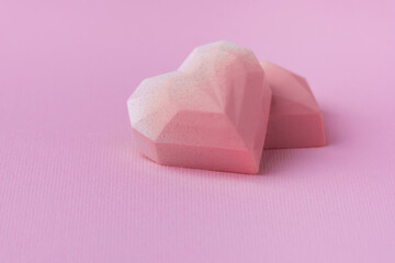 Set of homemade pink heart-shaped chocolate bonbons. Assortment of hand painted candies. Copy space. Macro shot of  chocolatier products on pink background. Happy Valentine's Day