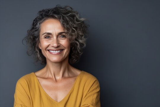 Smiling beautiful attractive mature woman looking at the camera of gray background. Generative AI
