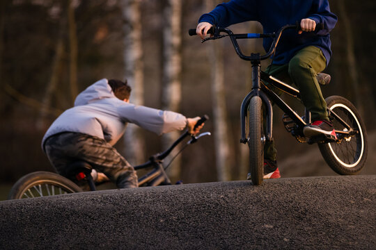 Closeup Kid boy with bicycle on a pump track park in sunset light. Asphalted bicycle race track, kids playground