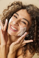 Woman beauty face close-up applying foam to wash and cleanse skin with fingers of her hand, nail and hair health, hair dryer style curly afro hair, body and beauty care concept