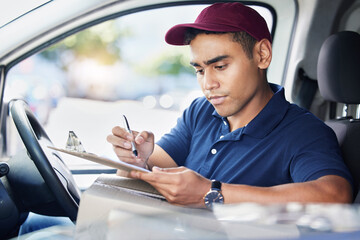 Planning his delivery route for the day. a young delivery man writing on a clipboard while sitting in a van.