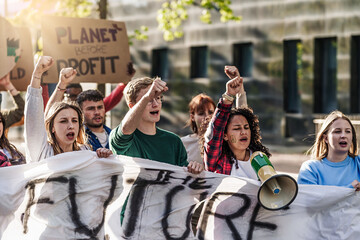 Youth Climate Protest - Young people marching with fists raised, megaphones, painted faces, and...