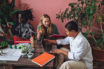 Diverse group of international students working on the urban project of modern city with renewable energy source, green areas. Concept of ecology, environment protection, waste recycling, technology