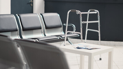 Empty reception desk in health facility with walking frame placed in hospital waiting area, support health care system. Medical diagnostic center with seats, disability friendly lobby.
