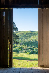 View of green landscape from inside doorway of rustic barn