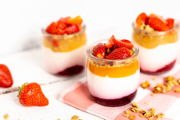 Fruit yogurt berry with muesli and fresh strawberries, on a white wooden background