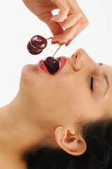 Cherries on the lips of a young beautiful woman on a white background