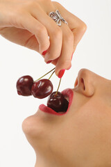 Young woman with cherries on her lips, isolated on white background
