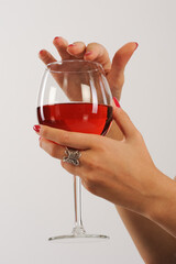 Woman's hand holding a glass of red wine on a white background