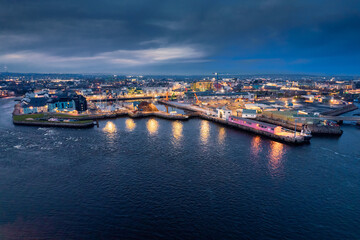 Fototapeta na wymiar Panorama image of Galway port at night. Aerial view. Popular educational center and tourist hub with vivid night life. Dark sky and light reflection in water.