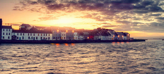 Panorama image of the Long walk area of Galway city, Ireland at sun rise. Dramatic cloudy sky with...