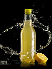 Splash over a plastic bottle with fresh lemonade on black background - 596099617