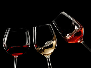 Red, white and rose wine glasses plash on black background - 596099619