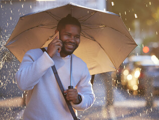 Ill meet you in a few minutes. a young businessman holding an umbrella while talking on a cellphone on a rainy day in the city. - Powered by Adobe