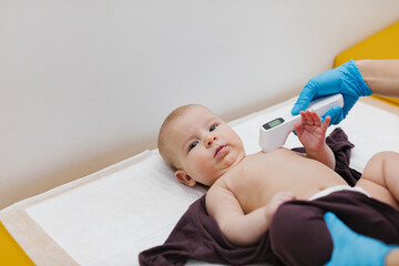 Pediatrician is measuring the child's temperature with a digital thermometer.