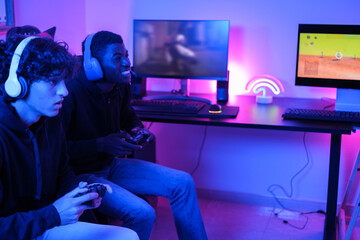 Two young teenagers playing video games online in their gaming room and playing with all the countries. Concepts: connection, teamwork, gamer