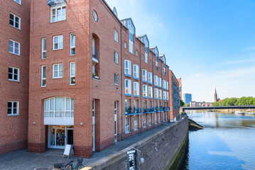 Renovated red-brick apartment buildings along a river on a sunny summer day