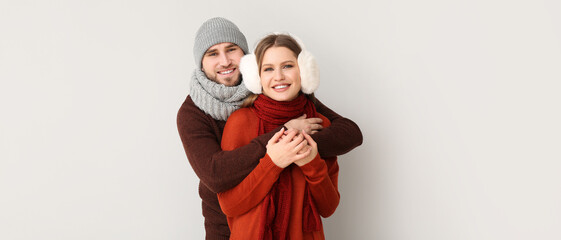 Fototapeta premium Portrait of happy couple in winter clothes on light background