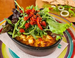 baked vegetarian lasagne with a lettuce and dehydrated tomatoes salad on the top in a gourmet restaurant, Lima Peru