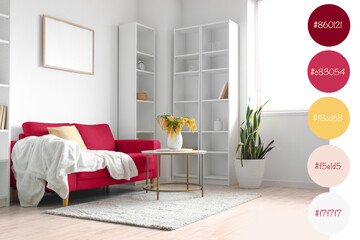 Vase with mimosa flowers on table and viva magenta sofa in interior of living room. Different color...