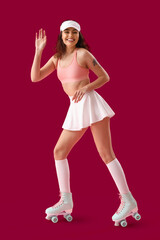 Young woman in roller skates on pink background