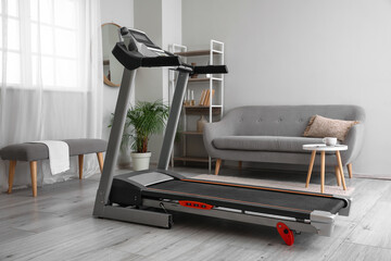 Modern treadmill in interior of light room