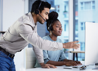 Dont panic, take your time. two young customer service agents having a discussion in the office and using a computer.