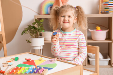 Cute little girl playing matching game with clothespins at home