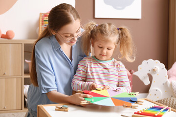 Mother and her little daughter playing matching game with clothespins at home