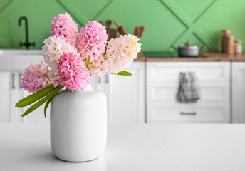 Vase with beautiful hyacinth flowers on white table in kitchen