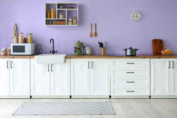 Interior of modern kitchen with white counters, sink and appliances