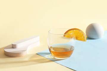 Glass of rum with orange slice and plaster figures on colorful background