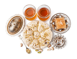 Tasty Tahini halva with pistachios, baklava and glasses of tea on white background