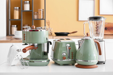 Set of modern household appliances on table in kitchen - obrazy, fototapety, plakaty