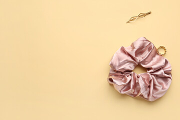 Silk scrunchy, ring and hairpin on color background