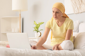 Mature woman after chemotherapy writing in bedroom
