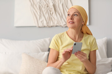 Mature woman after chemotherapy using mobile phone in bedroom