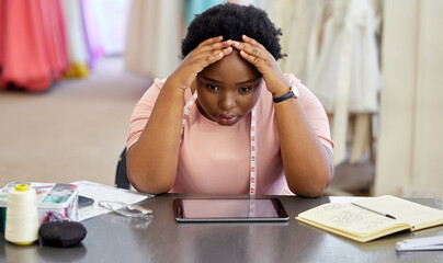 How am I gonna get through this. an attractive young seamstress looking stressed while working in...