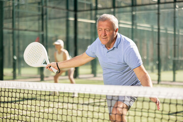 Fototapeta premium Mature sporty man playing padel game in court on sunny day