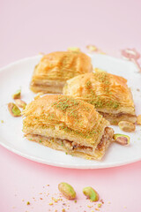 Plate with tasty baklava on pink background, closeup