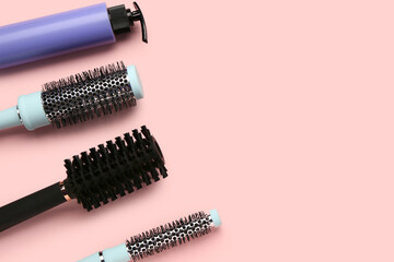 Hairdresser's brushes with spray on pink background