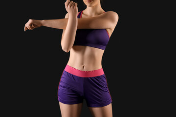 Sporty young woman in shorts on black background