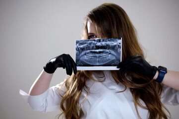 Girl holds her X-ray with a panorama of baby teeth and the second row of replaceable molars. Two...