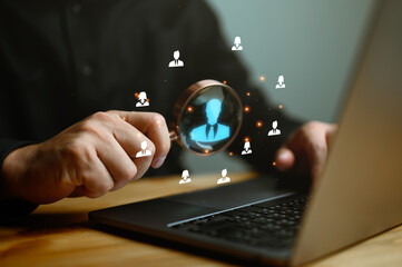 Human Resource Management, HRM, Businessman holding magnifier for searching to human icons for human development and recruitment concept. Customer Relationship Management, customer network technology