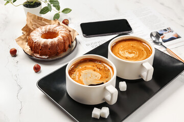 Tray with cups of coffee, sugar, cake, newspaper and mobile phone on grunge background, closeup